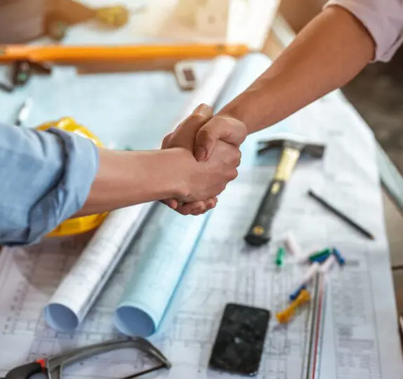 Handshake over construction plans and tools.
